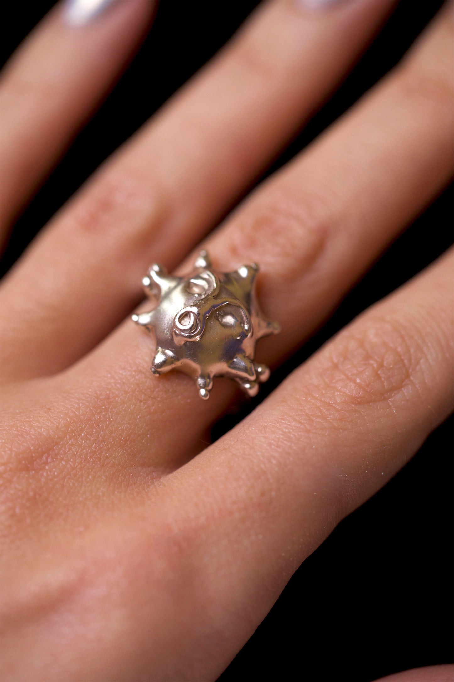 Tempest Ring by CLARK on model’s middle finger. The personified face with a spiral mouth is clearly seen. The Sol ring by CLARK is worn on the ring finger. Both rings are Sterling Silver.