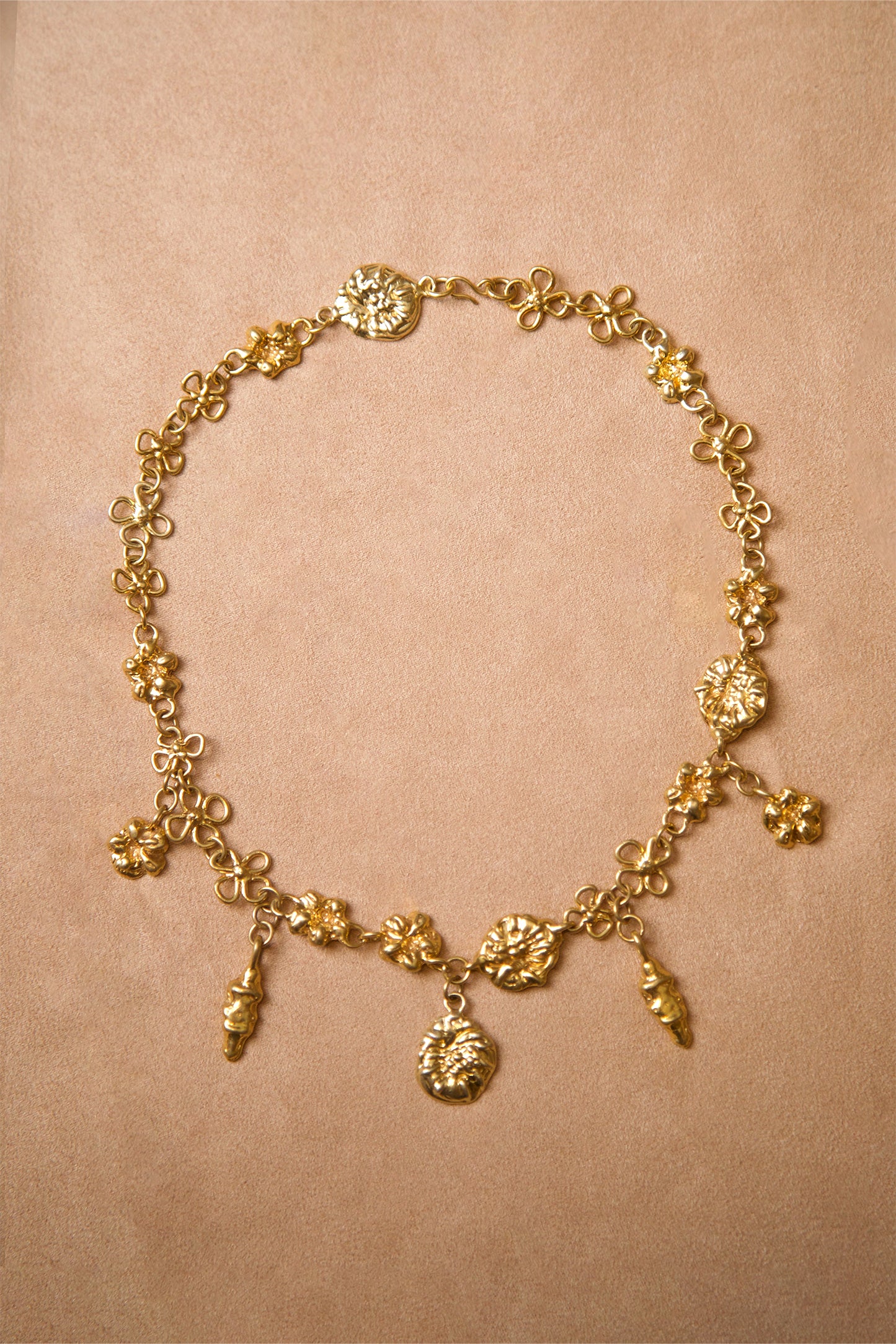 Product photo of Earthly Delight Necklace by CLARK in 18K Gold Vermeil. This unique luxury necklace features multiple gold charm talismans hanging from floral chain links, all handcraft using the lost wax casting method.