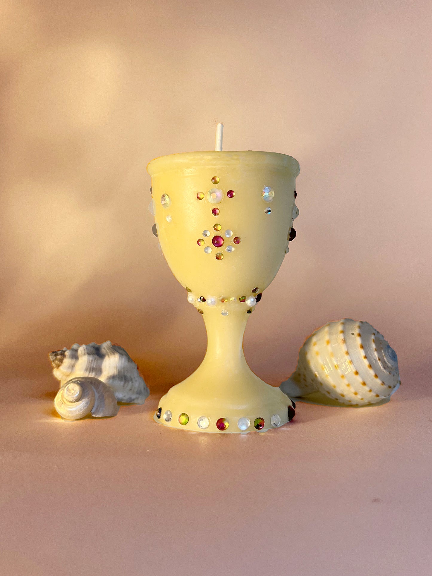 An adorned drinking vessel, shaped like a cup with multi-colored gem embellishments. Hand-poured and made from 100% beeswax. Small-batch and a perfect gift for someone looking for an eco-friendly and artisanal candle.