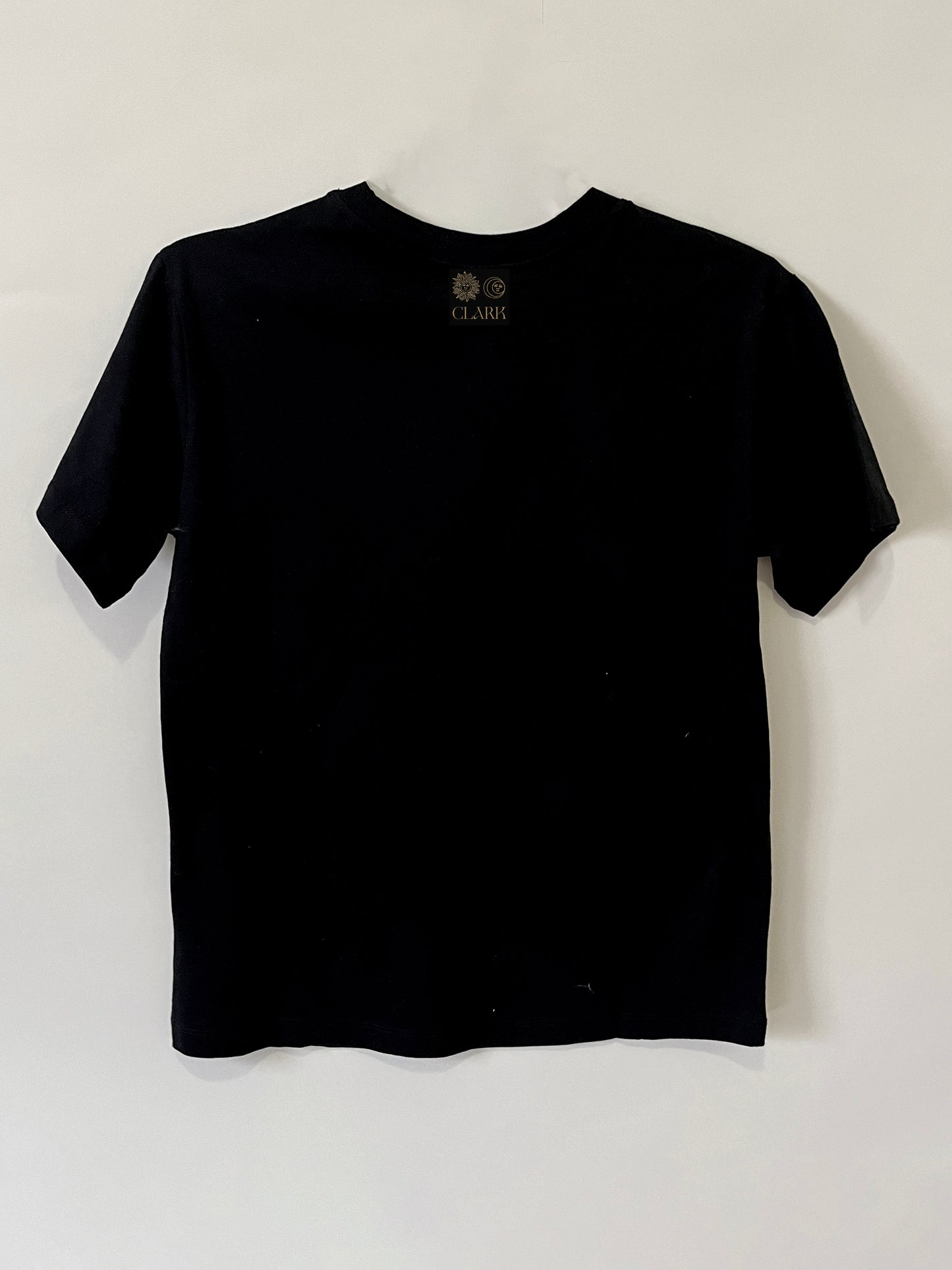 Product photo of Happy As A Clam tee by CLARK. The Back view of straight-cut black tee with CLARK logo printed in gold at neck. Logo is of Sun and Moon with CLARK underneath.