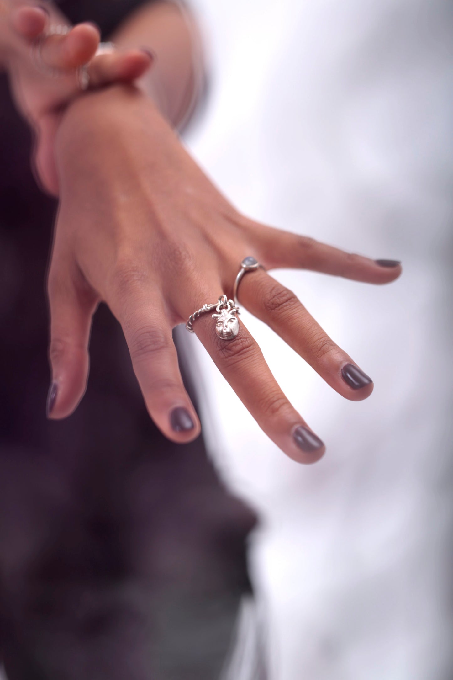 Model wears a Lilith Charm Ring by CLARK on her index finger. Model is also wearing a Magic Moonstone ring by CLARK. Both rings are cast and polished in Sterling Silver.