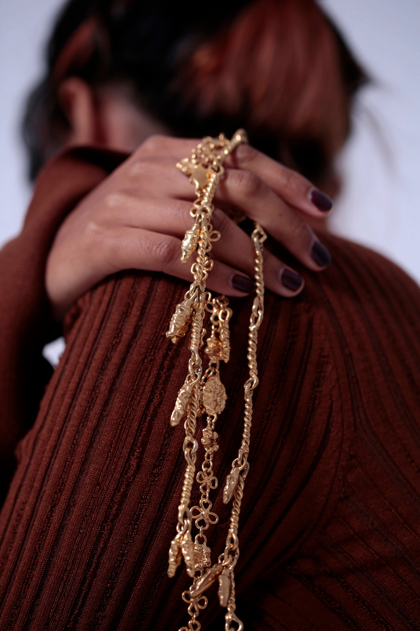 Model posing with various 18K Gold Vermeil CLARK statement necklaces in her hand. The intricate sculptural hand crafted detail is clear. All the unique adornments make a beautiful coordinated set.