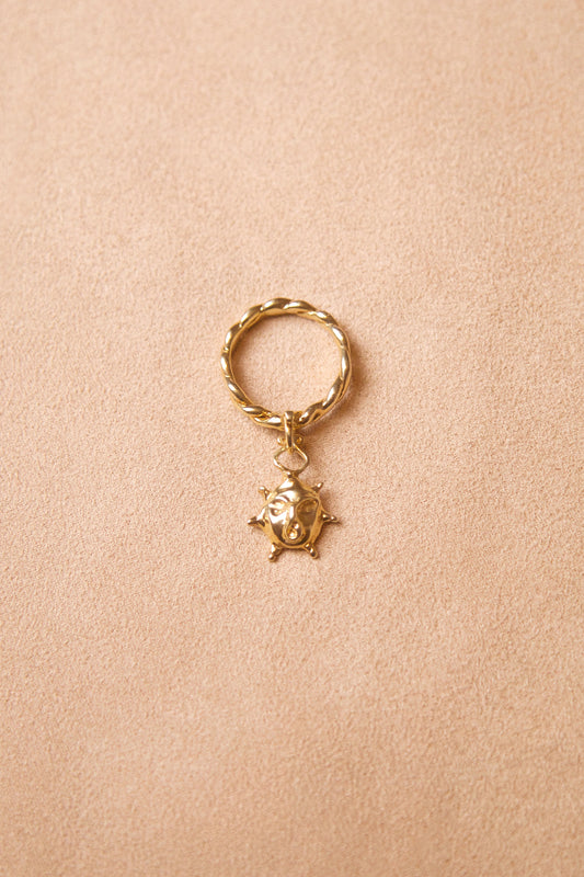 CLARK Aurora Charm ring rests on pink suede. The ring features a twisted 18K Gold Vermeil band with a sun face charm. This is a unique statement ring made using the lost wax casting method. A radiant gift for someone who likes renaissance inspired jewelry. 