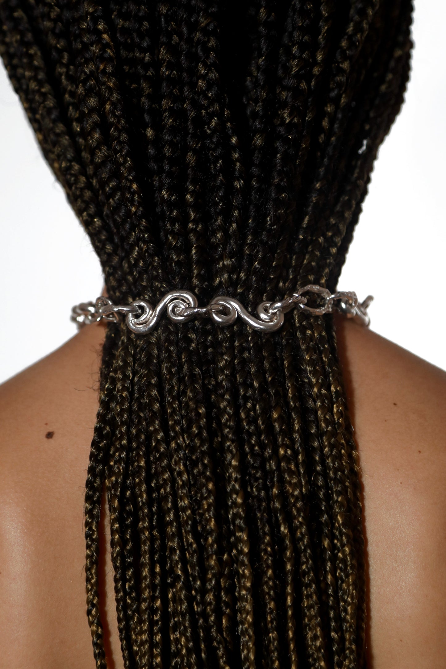 Product photo of CLARK Braided Waves Necklace. This organic and oceanic necklace features spiraling links connected to form a chunky choker chain, exuding a unique and striking appearance of curling silver links, like the ocean tide. 