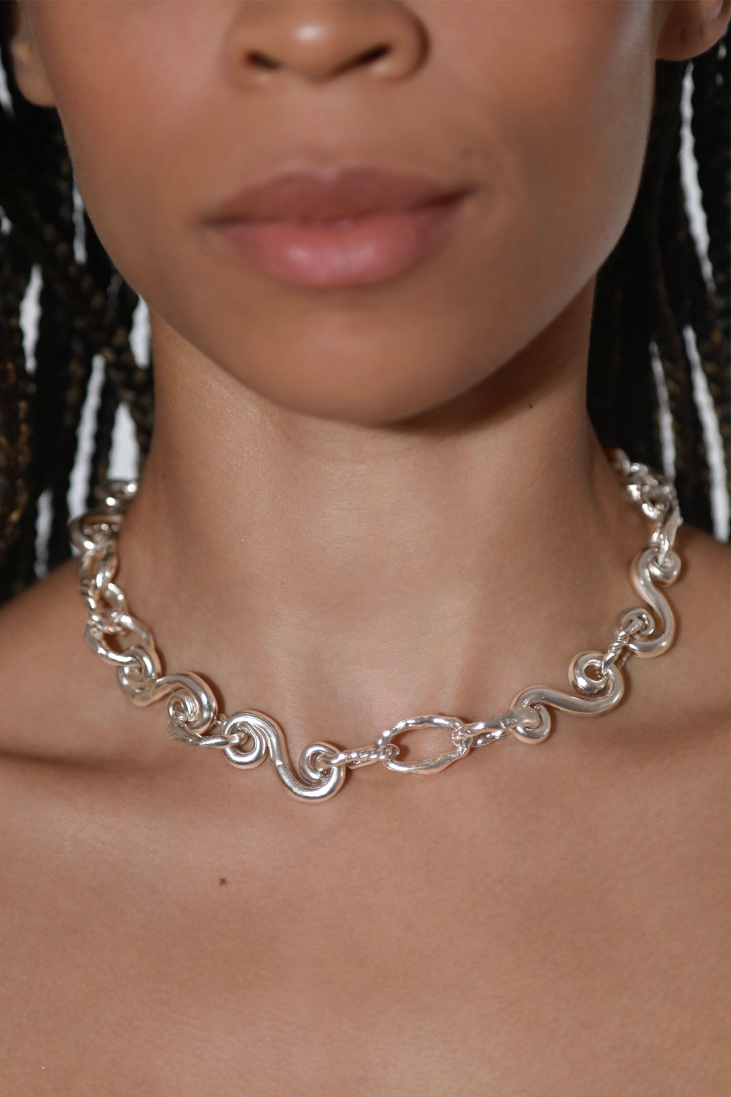 Detail of Braided Waves Necklace by CLARK in Sterling Silver on a model. Pictured is an organic spiraling chain link finished in high polish. 