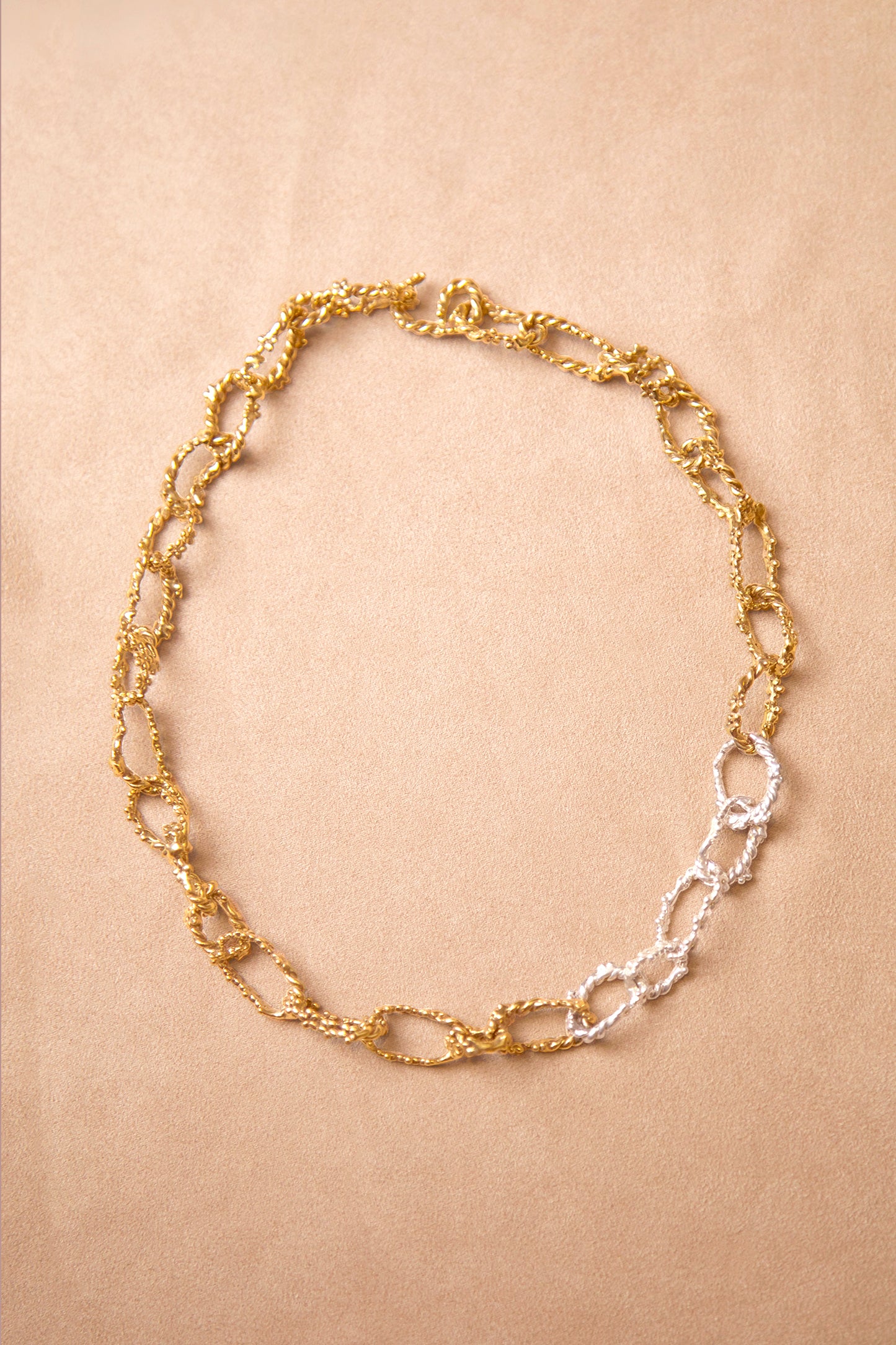 This one-of-a-kind necklace features interlocking braided chains in silver and gold, creeping vines adorned with tiny flowers. Handmade in Brooklyn.