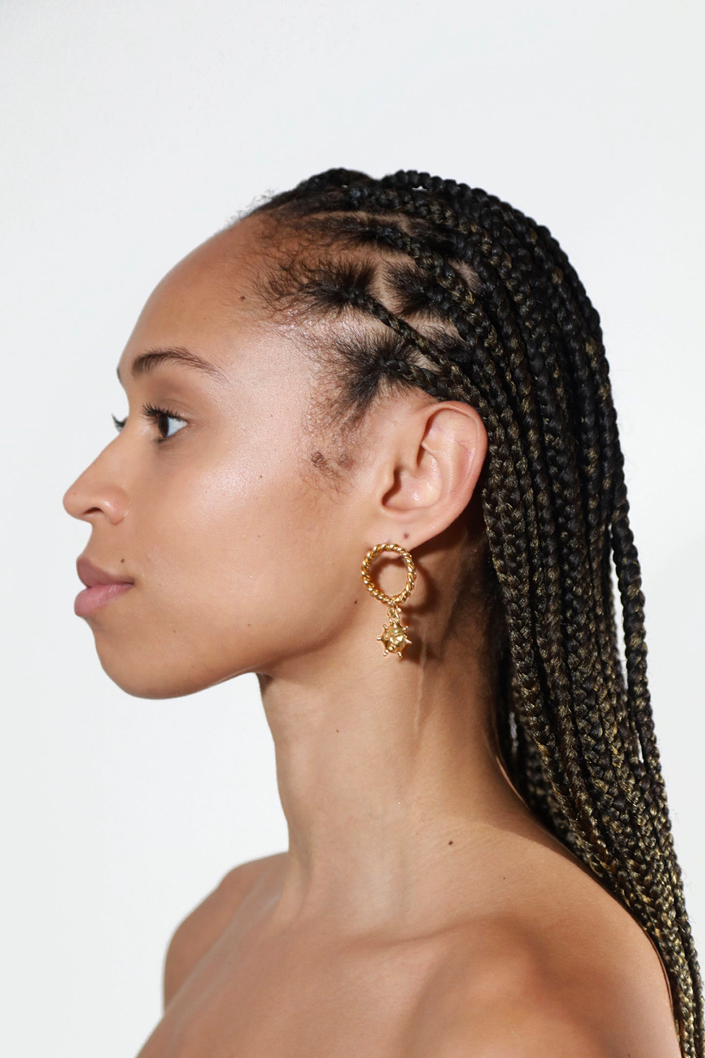 Model wearing 18K Gold Vermeil Ouroboros Earrings by CLARK. These one-of-a-kind renaissance jewels reference a sun motif as a unique handmade charm.