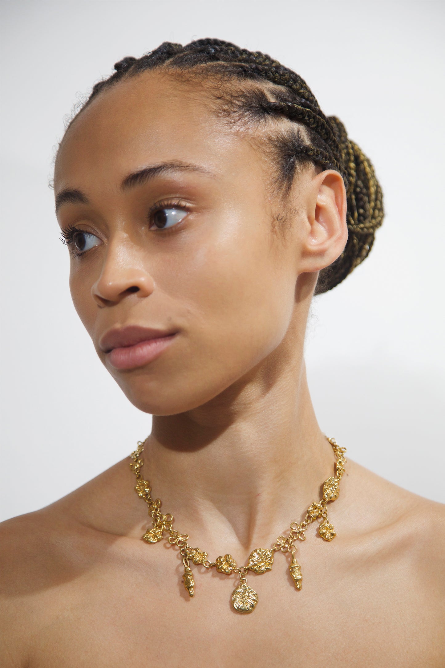 CLARK Earthly Delights Necklace on model. Five 18K Gold Vermeil charms delicately adorn the models neck. These are the perfect occasion jewelry pieces to wear to a wedding, anniversary or special celebration. 