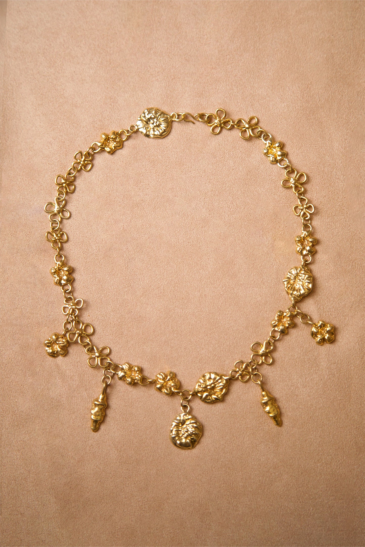 Product photo of Earthly Delight Necklace by CLARK in 18K Gold Vermeil. This unique luxury necklace features multiple gold charm talismans hanging from floral chain links, all handcraft using the lost wax casting method. 