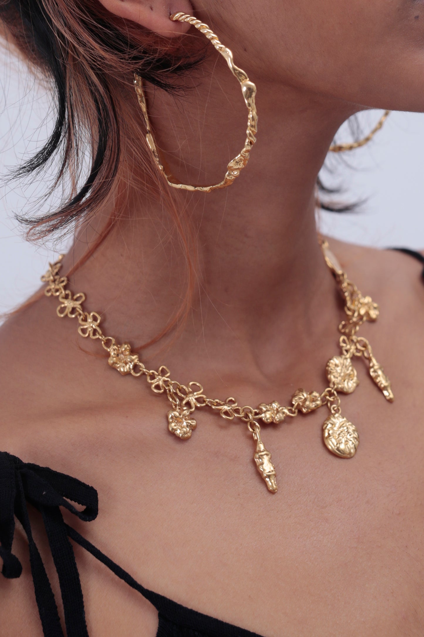 CLARK Earthly Delights Necklace on model. Four 18K Gold Vermeil charms hang off delicately around the models neck. She is also wearing Sea Siren Hoop Earrings. These are the perfect occasion jewelry pieces to wear to a wedding, anniversary or special celebration. 