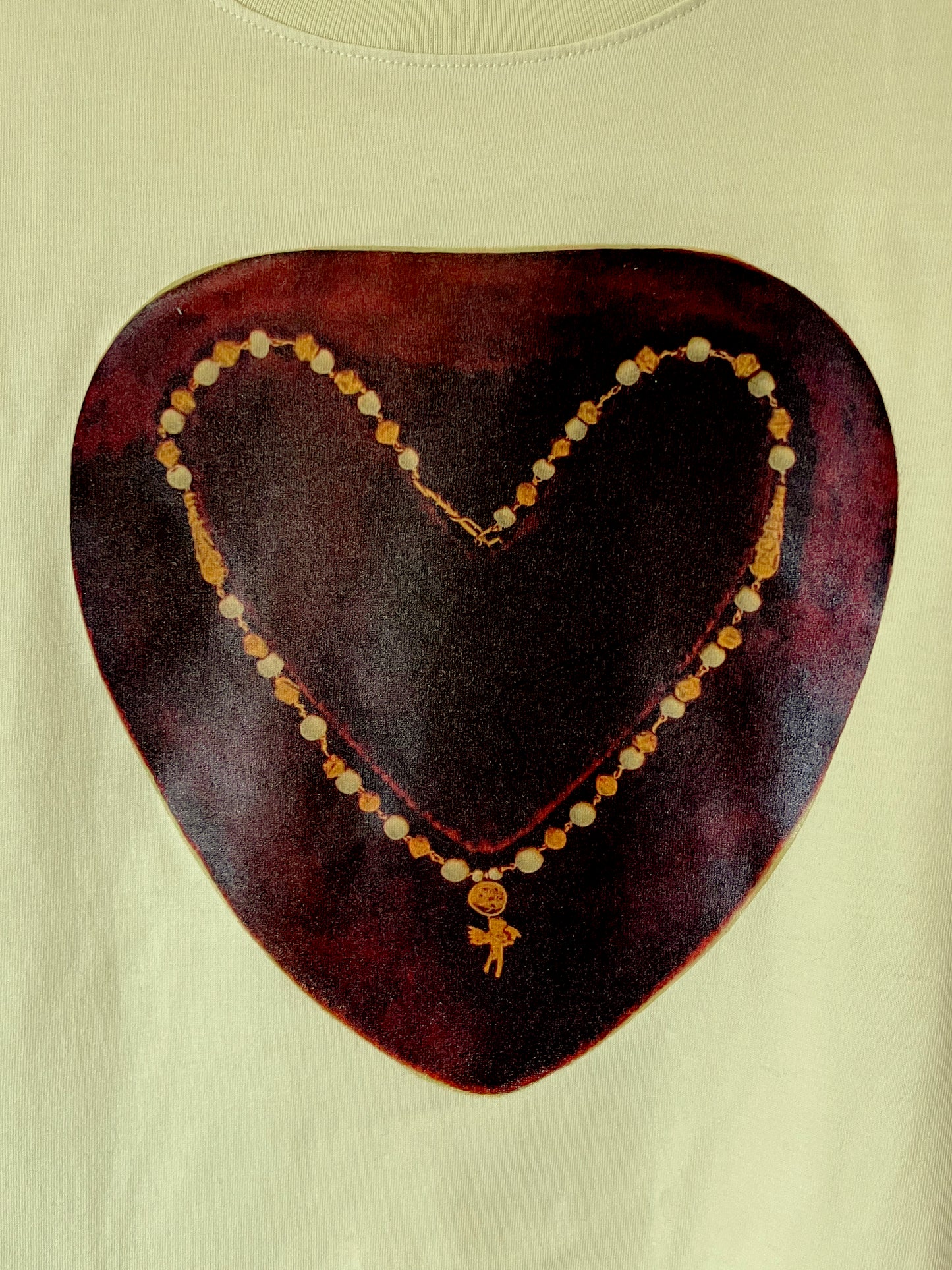 Close up of whimsical design - a photo collage of a necklace with an angel charm in the shape of a heart on a red ground. This shirt is lemon (yellow) style. A perfect gift for someone who loves  to mix renaissance atheistic and streetwear. 