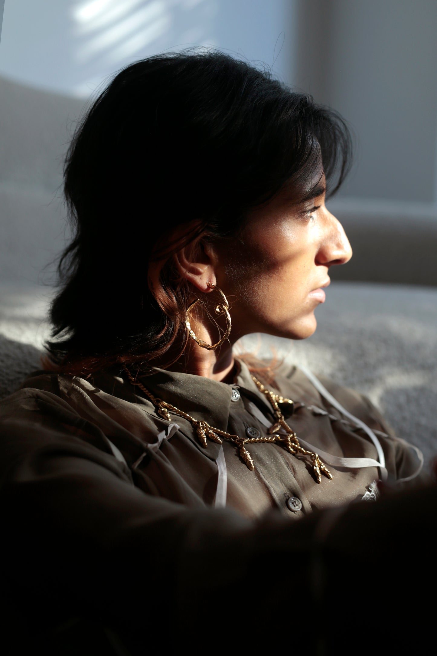 Model looking out the window in CLARK jewelry. The afternoon light hitting the organic and nature-inspired unique statement jewelry feels like a luxury unique jewel and reminiscent of Renaissance adornments. 