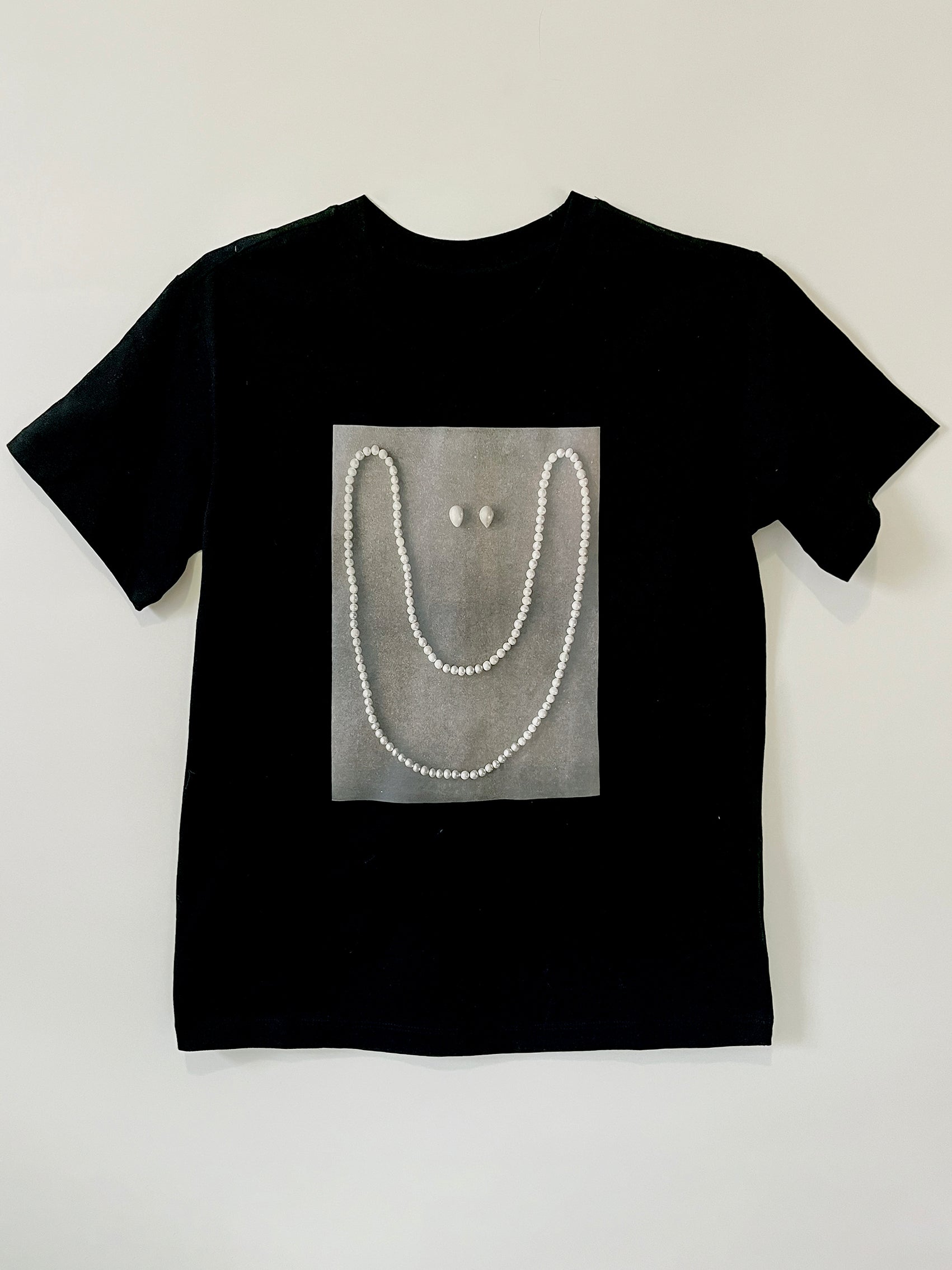  Product photo of Happy As A Clam tee by CLARK. A graphic custom-made black straight-cut shirt featuring a smile made out of pearls. It is an artist made to order item, available in s/m and l/xl.