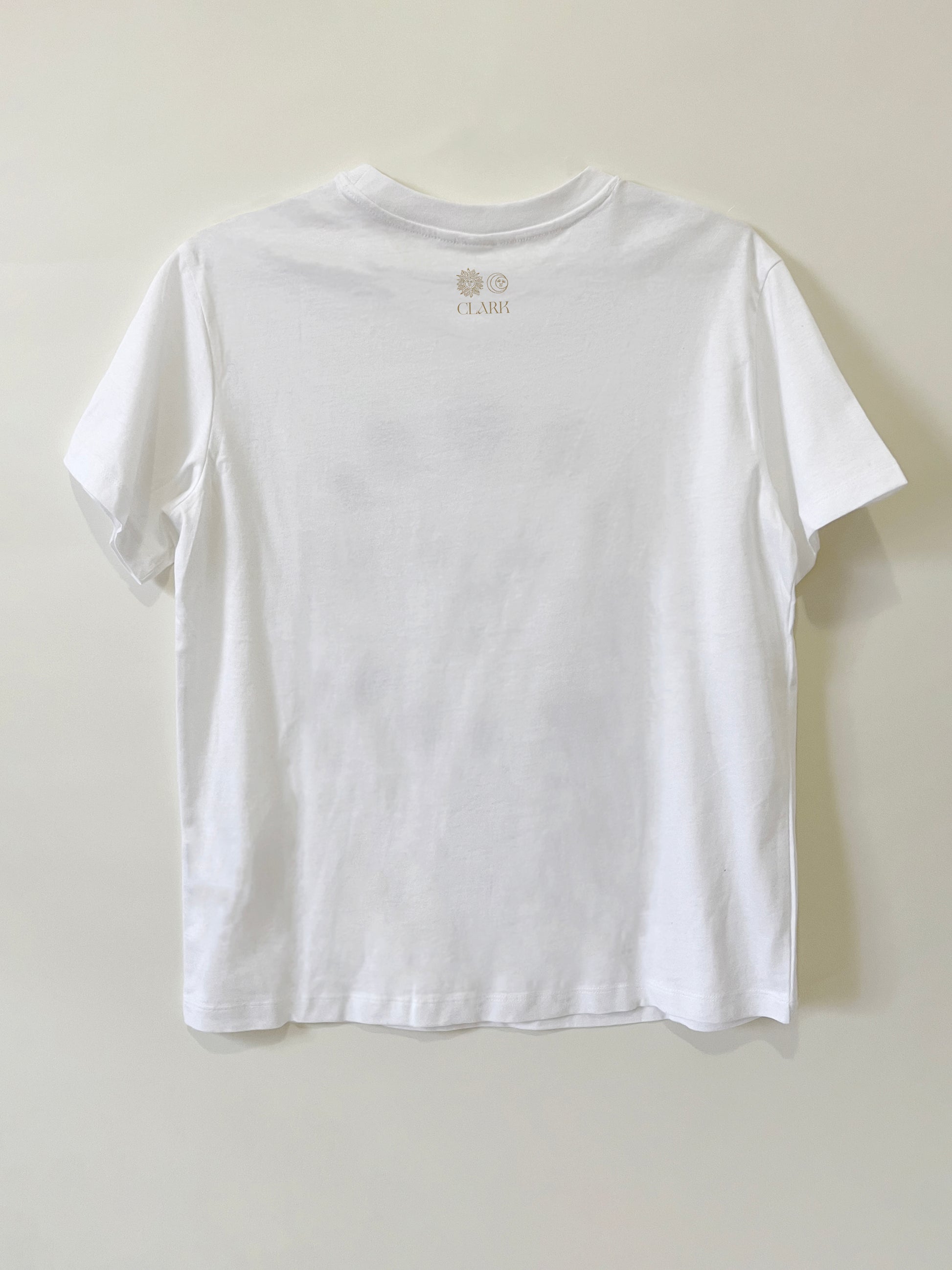 Product photo of Heartbreaker tee by CLARK. The back view of straight-cut white tee with CLARK logo printed in gold at the neck. Logo is of Sun and Moon with CLARK underneath. 