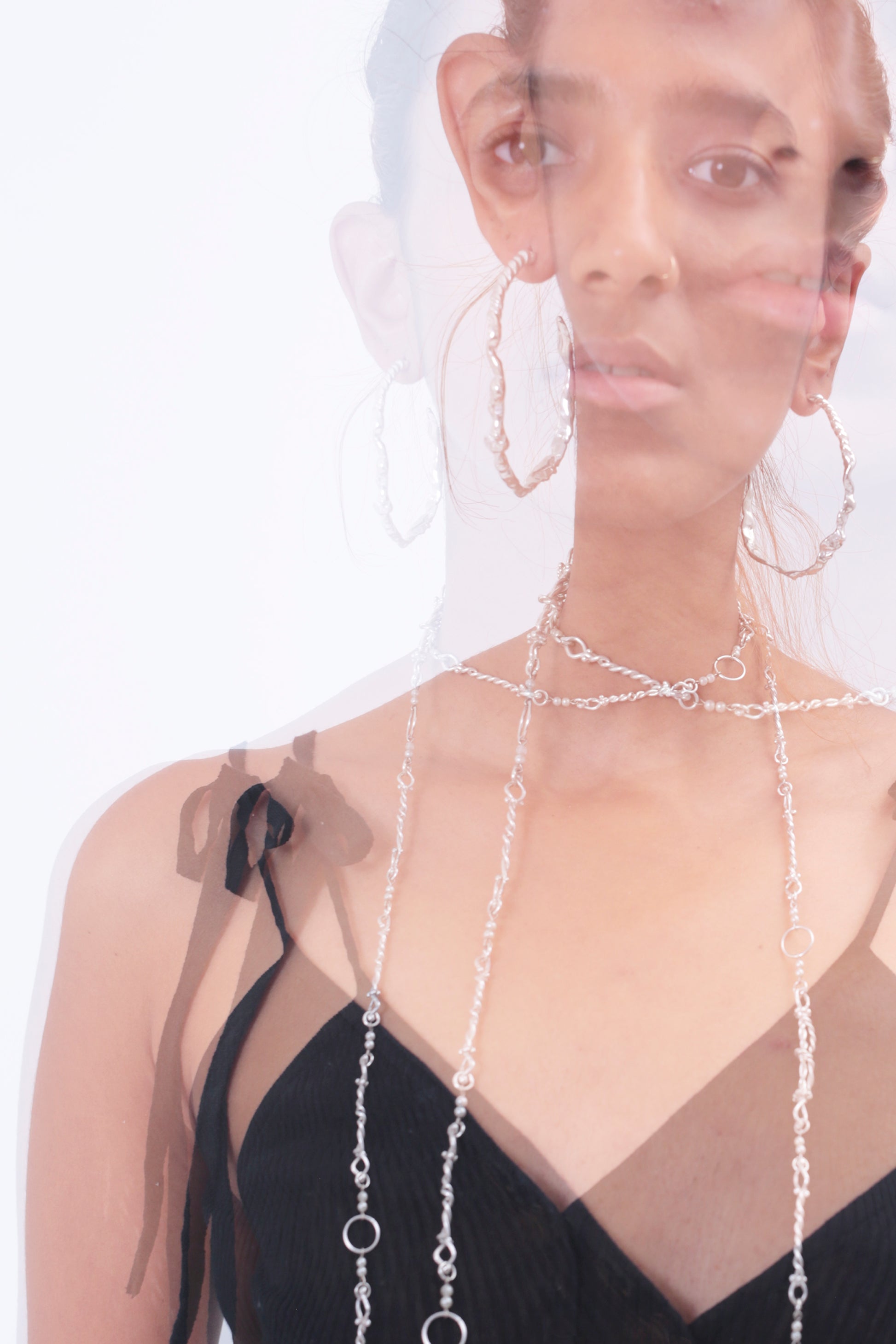 Double exposure mood photos of model, Aayushi Khowala, wearing CLARK Sterling Silver Sea Siren Hoop earrings. The mood is elevated and elegant as well featuring Renaissance inspired jewelry. 