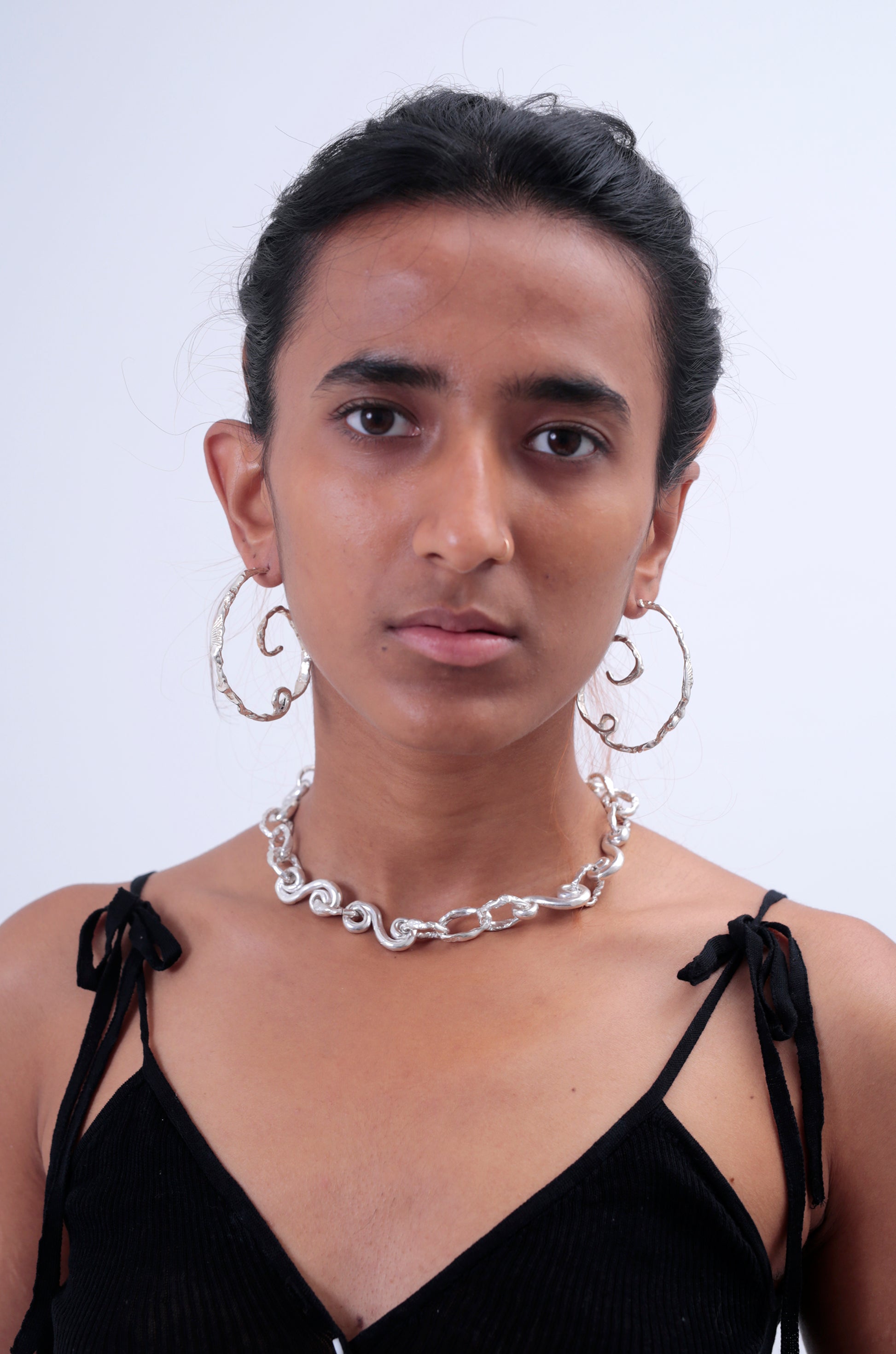Front view of model wearing CLARK Andromeda Earrings. These spiraling, organic hoops are a statement and inspired by the spiral of the Andromeda galaxy. You can see the unique shape well face on. 