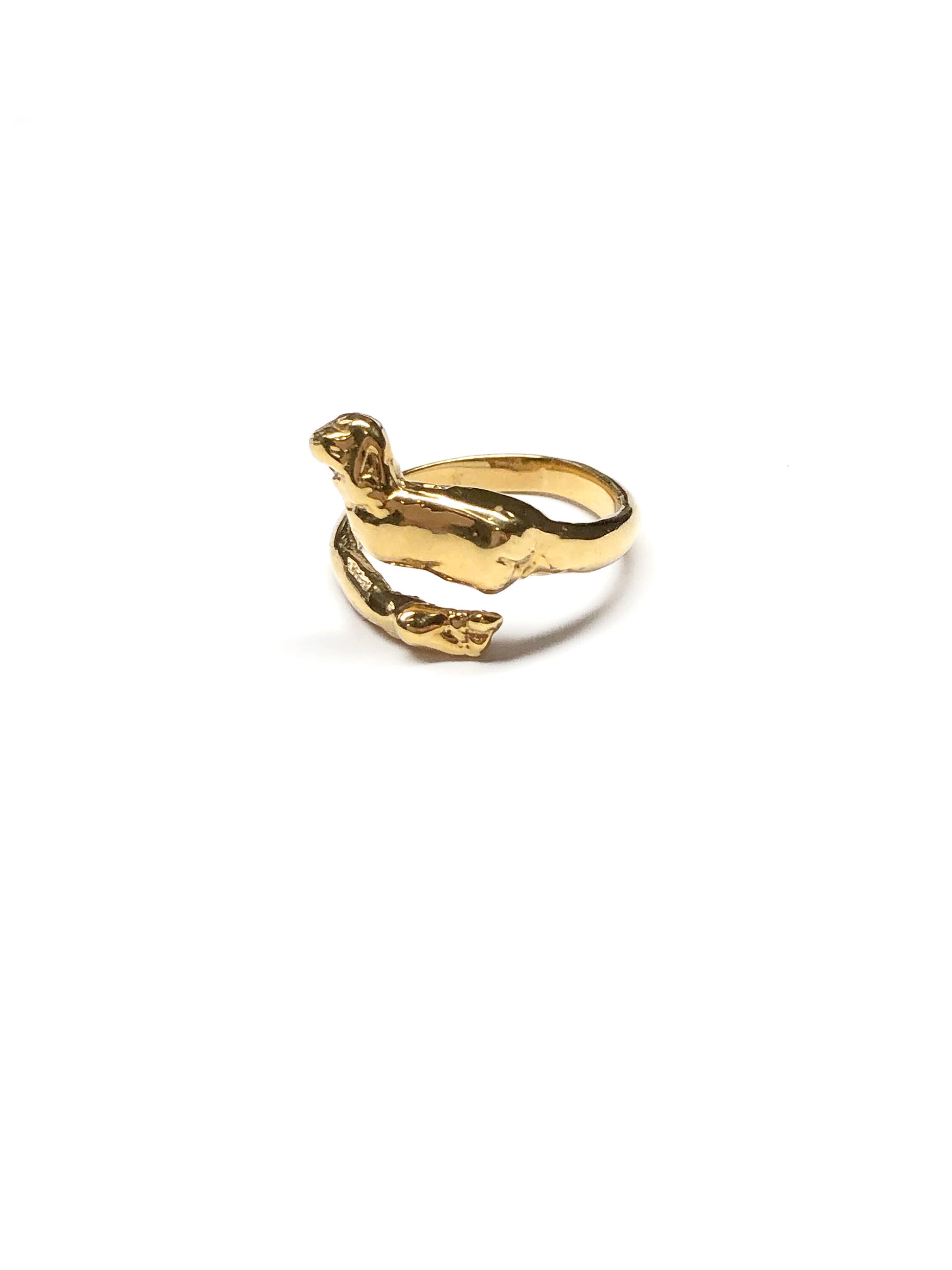 Product photo of 18K Gold Vermeil Cupid Ring by CLARK photographed on white ground. Gold band is a cheeky personification of cupid. The top, a wing in flight with a little butt and the bottom a small foot. Flexible band allows for the ring to be adjustable. 