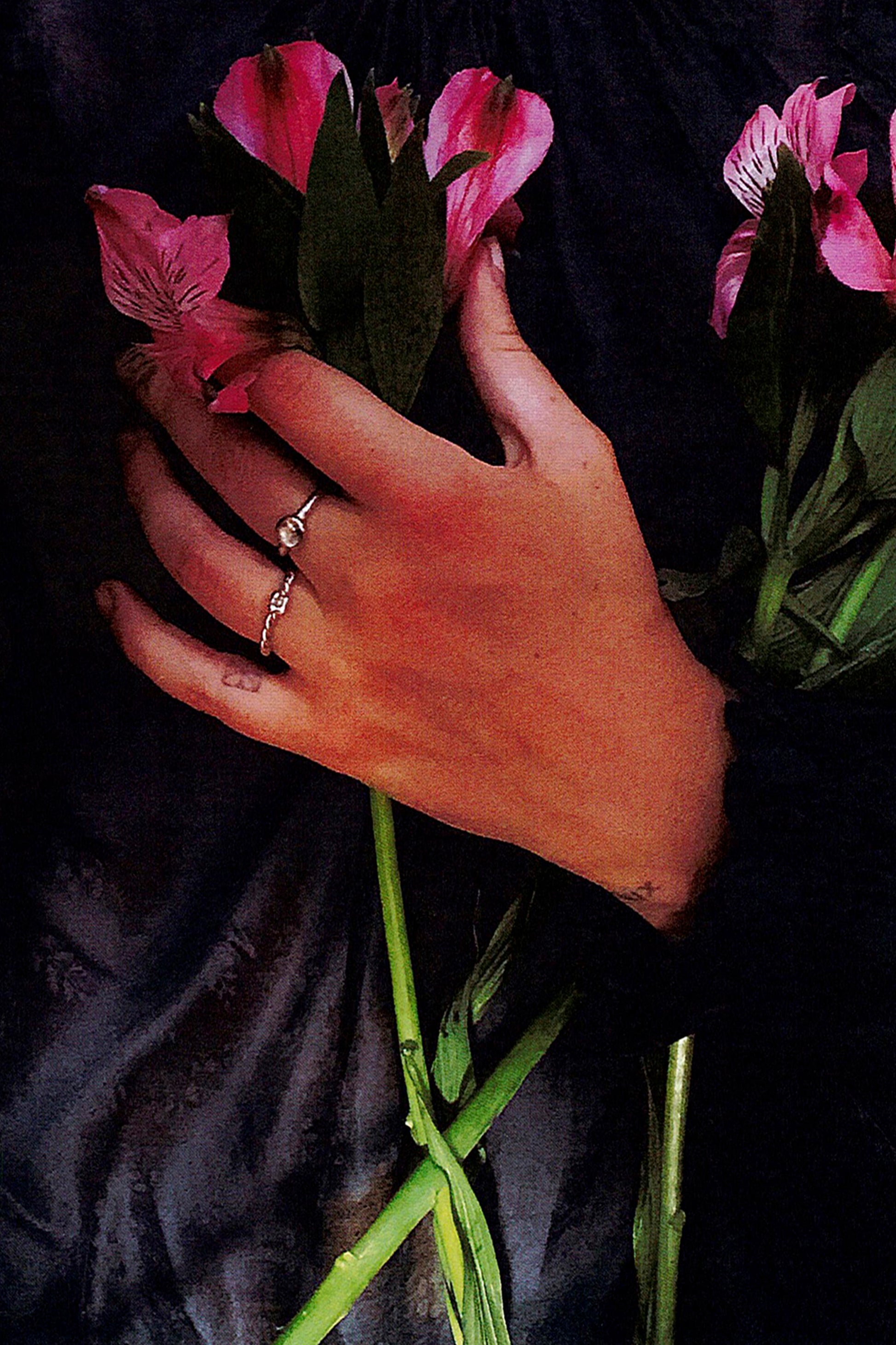 Mood photo of a model wearing CLARK mini Mermaid Ring and holding a bouquet of flowers to her chest. The feeling is romantic, Renaissance-inspired.