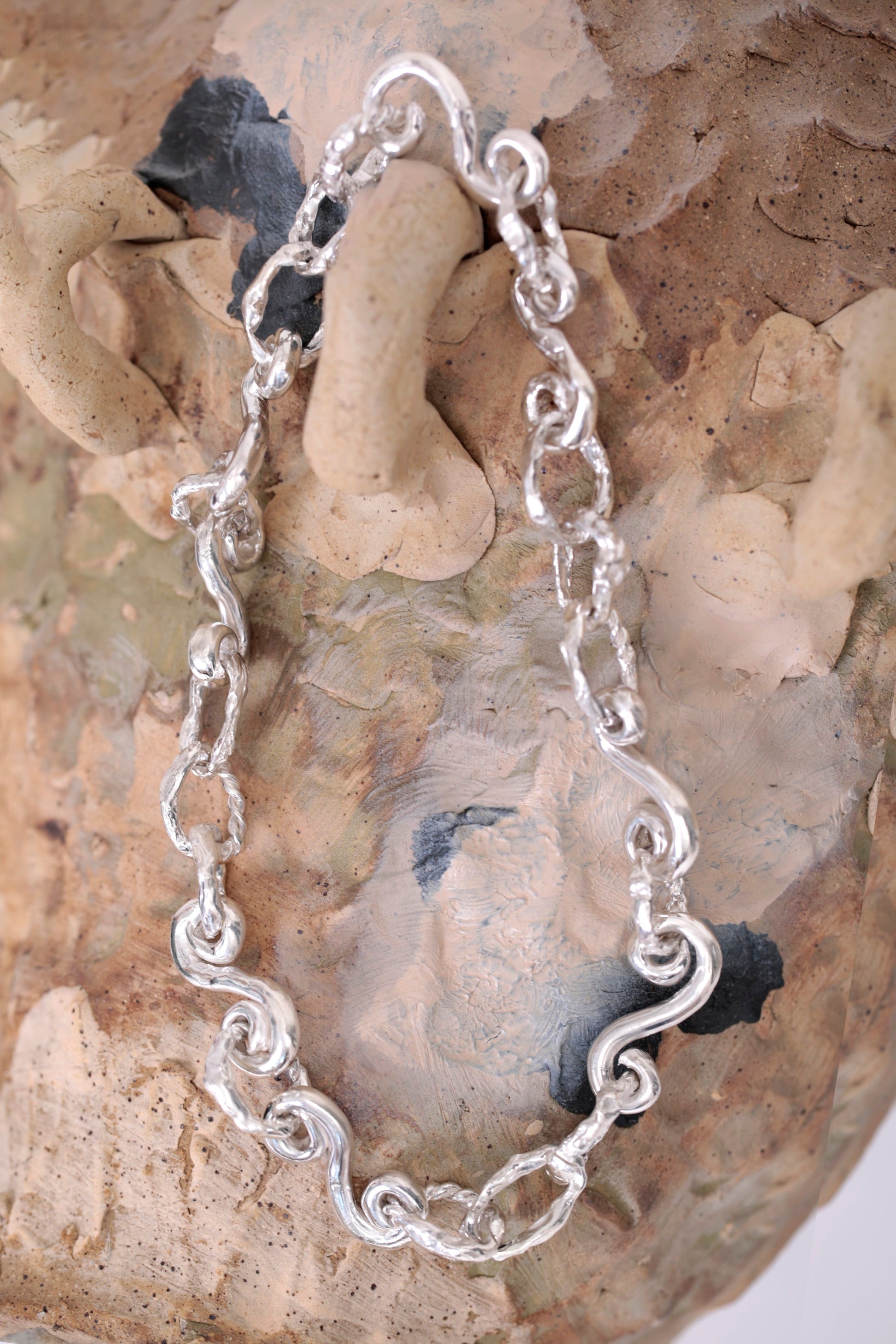 Product photo of CLARK Braided Waves Necklace. This organic and oceanic necklace features spiraling links connected to form a choker chain, exuding a unique and striking appearance that is sure to make you stand out from the crowd.
