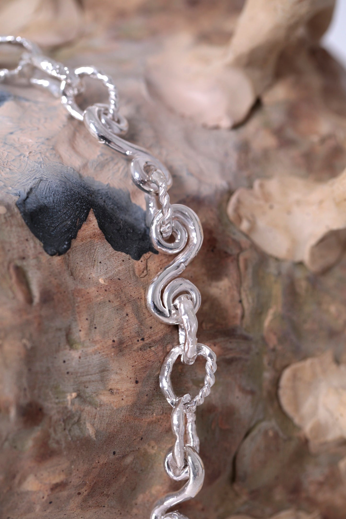 Detail of Braided Waves Necklace by CLARK in Sterling Silver. Pictured is an organic spiraling chain link finished in high polish. This necklace is a love letter to the ocean floor, a tribute to its beauty, mystery and forgotten treasures. It is a one of a kind necklace, created in Brooklyn using the lost wax casting method. 