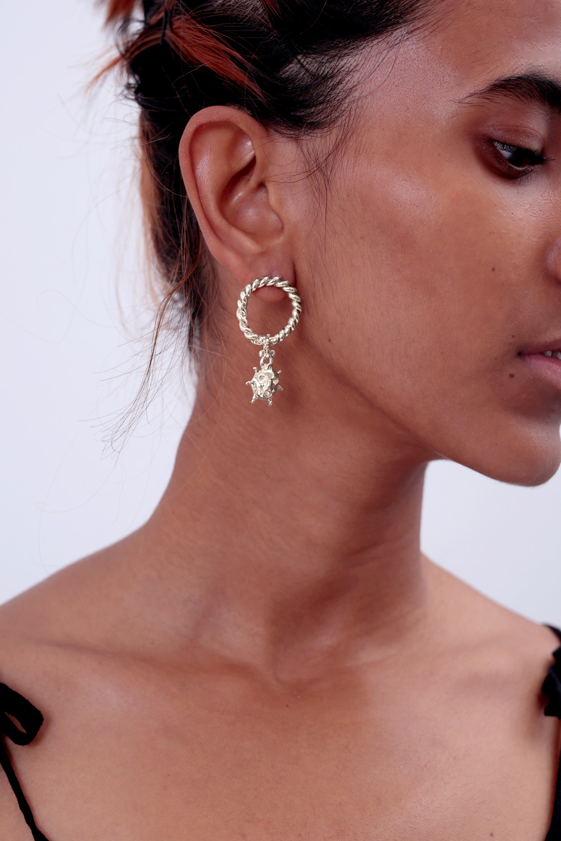 ¾ view or model wearing Sterling Silver CLARK Ouroboros Earring. The artist Zoe Clark made the sun charm and one-of-a-kind twisted hoop. These statement earrings are created using the lost wax casting method. 