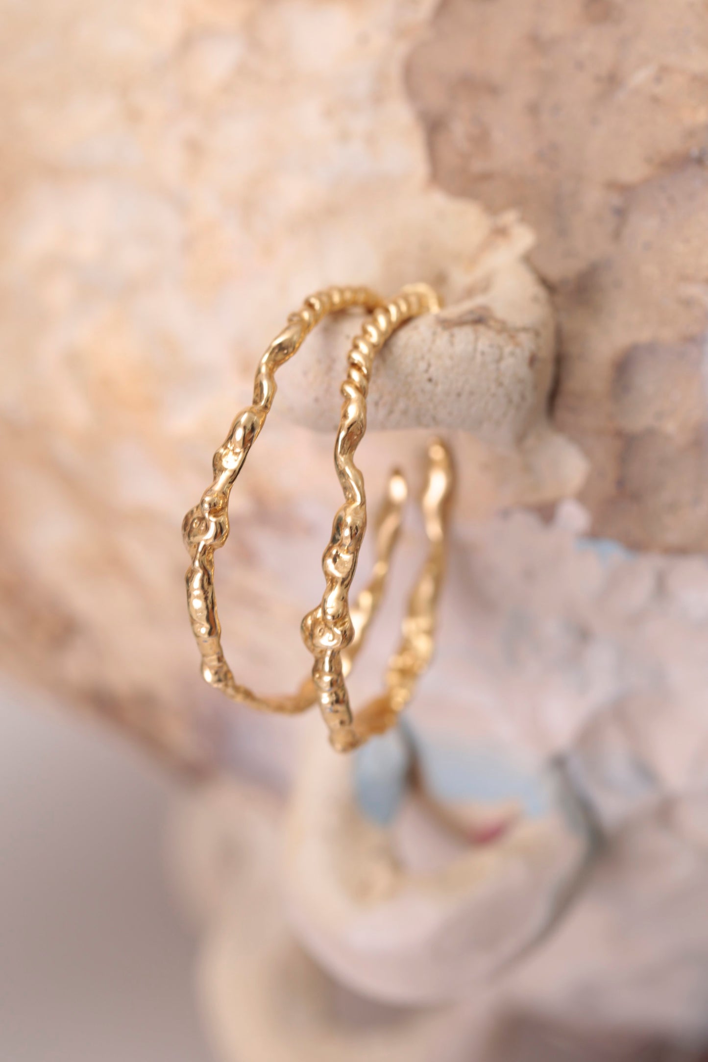 ¾ View of CLARK Sea Siren Hoop earrings, clear impressions of seashells and seafloor treasures are highlighted. These one-of-a-kind statement earrings are made using the lost wax casting method by an artist in Brooklyn. 