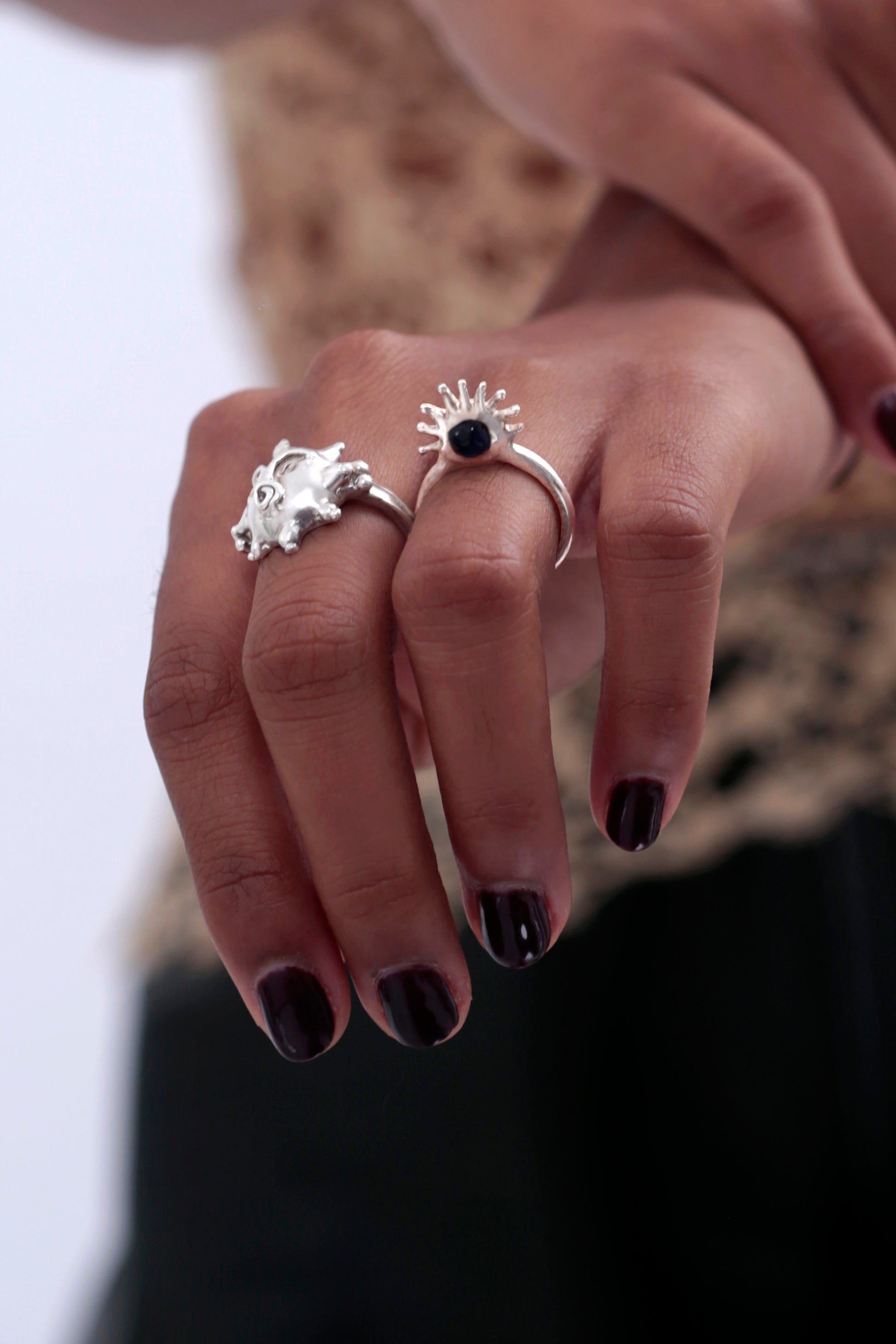 Model is wearing a sculptural Sol Ring by CLARK. The photo shows the starburst design with high quality Sterling Silver rays like a sun around a luxurious purple gemstone. This is a statement handmade piece of jewelry handcraft using the lost wax casting method. 
