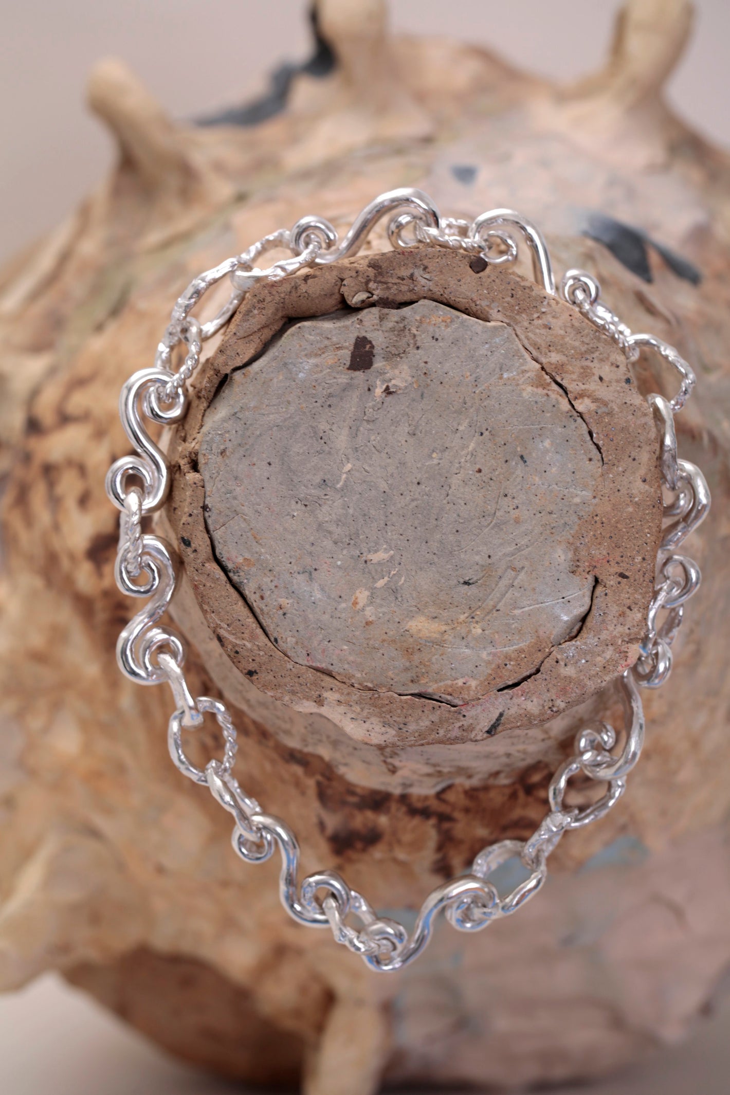 Braided Waves Necklace by CLARK. One-of-a-kind Sterling Silver necklace hanging on a ceramic pot. Spiral links and sea-formed rings joined in a long chain necklace and finished in a high polish.