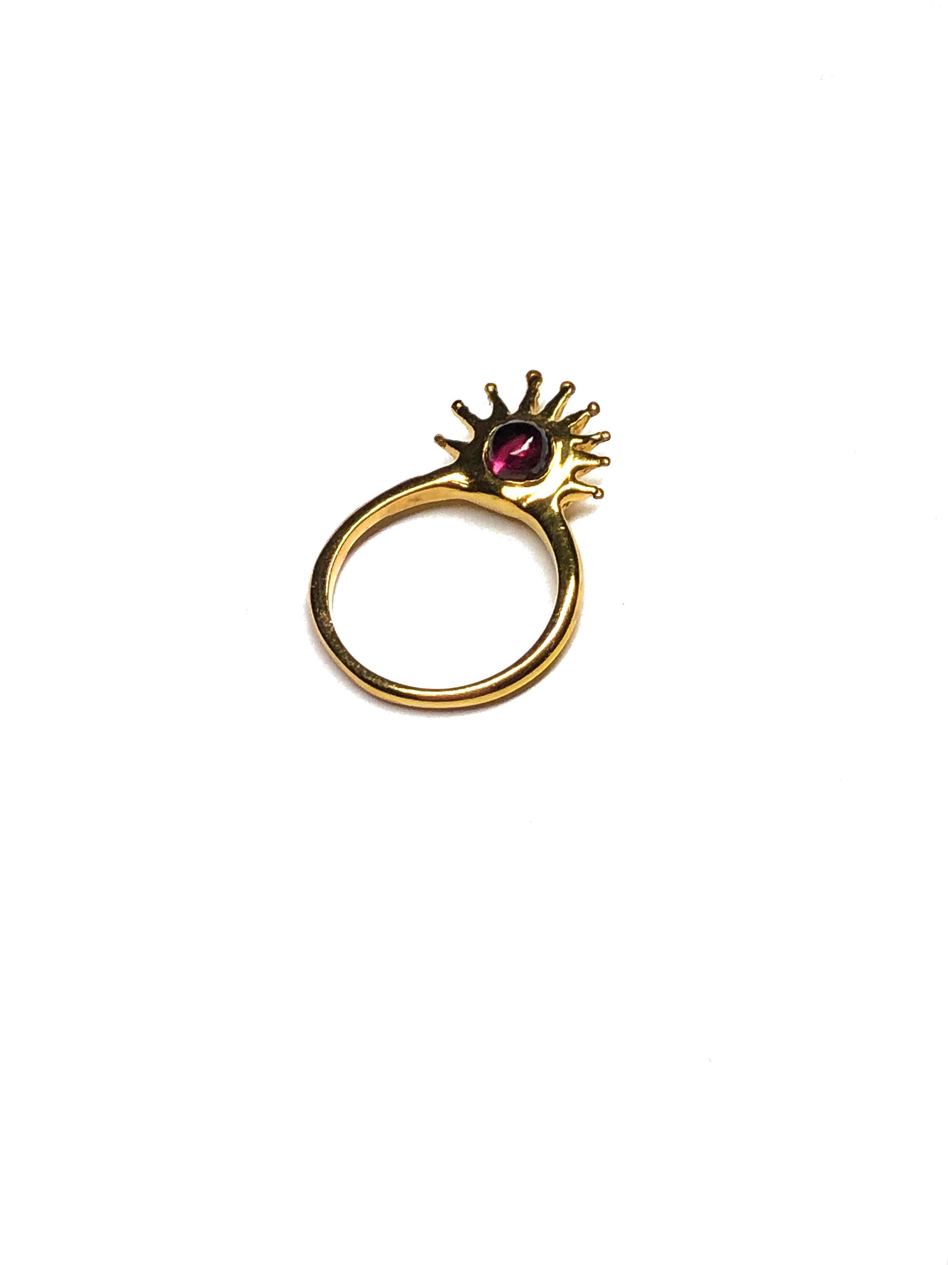 Product photo of Sol Ring by CLARK in 18K Gold Vermeil. This ring is on white ground and highlights dynamic sun design. This occasion jewelry item has a garnet gemstone, perfect gift for a January birthday or any celebration or wedding. 